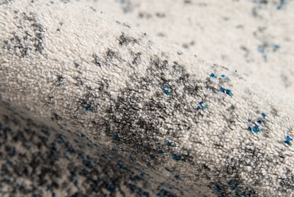 Ivory tufted area rug with gray speckles and blue flecks; loft-style 5' x 8' area rug.