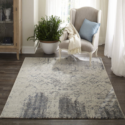 Cream woven area rug with gray-blue distressed pattern in a cozy living room with a beige wing chair and blue pillow.