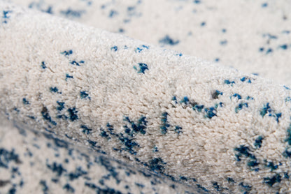 Cream shag rug with blue speckled pattern & plush textured pile; modern abstract design.