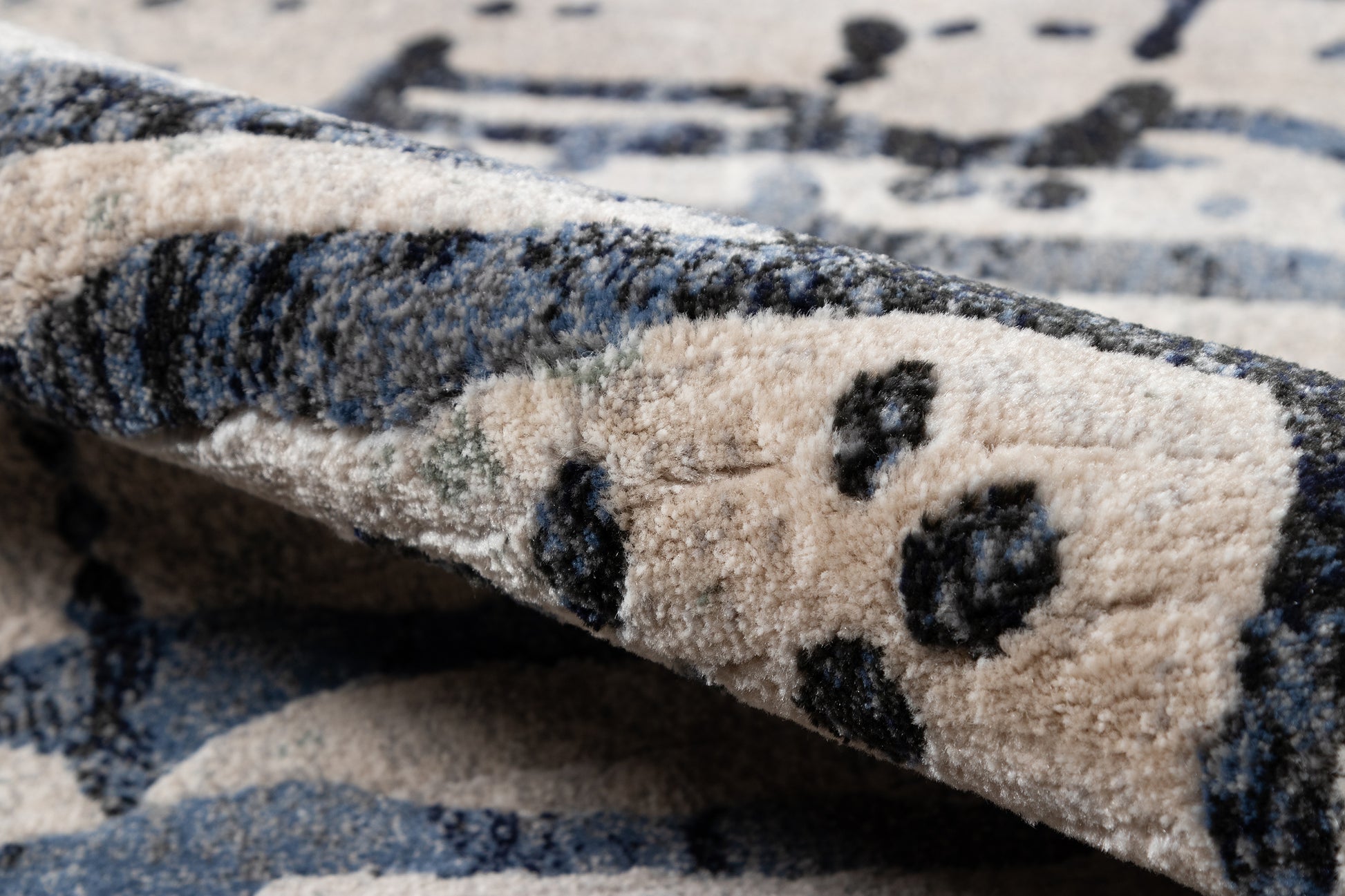 Beige and gray-blue runner rug with dark navy geometric pattern; plush pile and folded edge.
