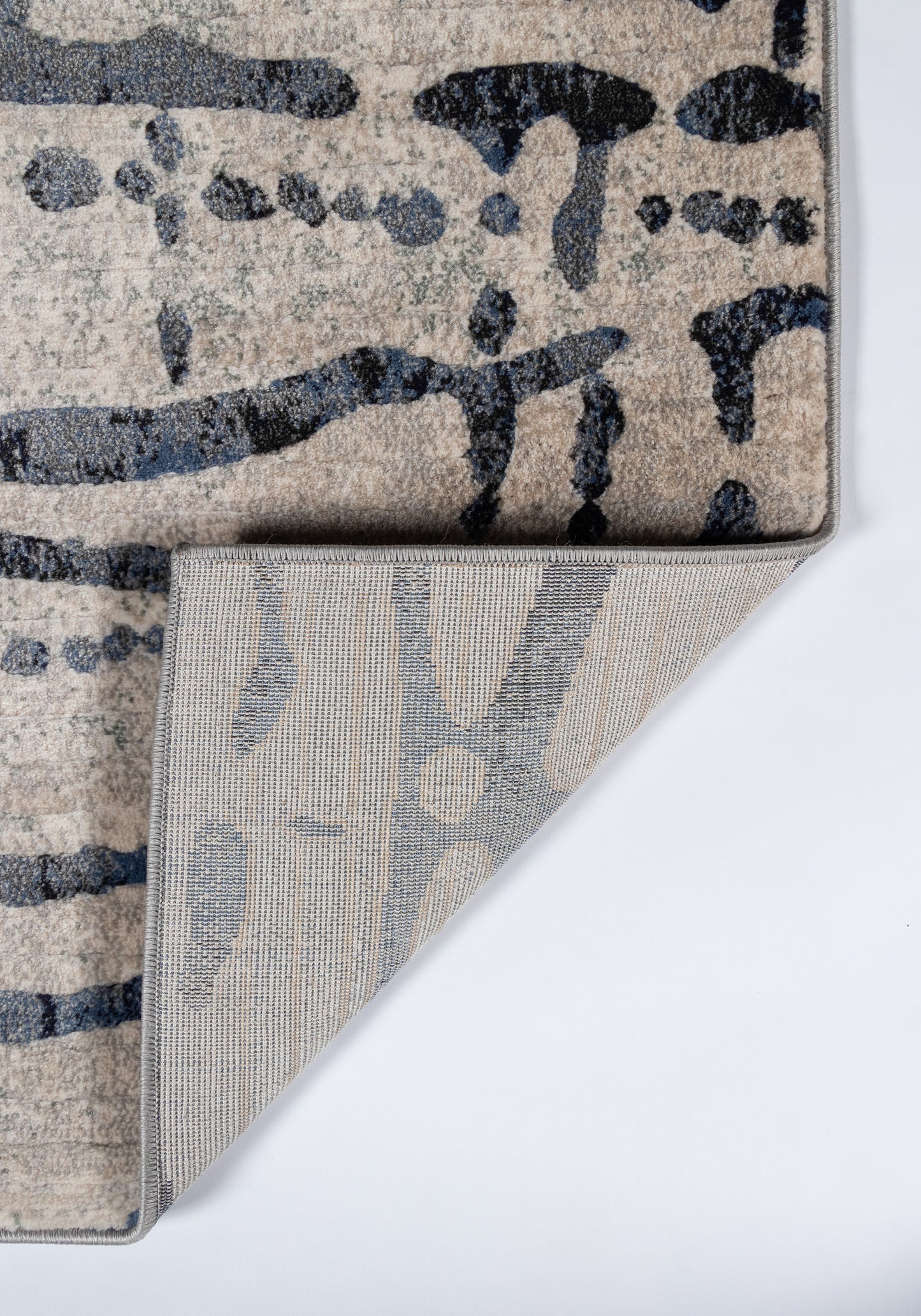 Abstract gray and beige runner rug with navy brushstroke pattern; plush pile, folded corner reveals gray underside.