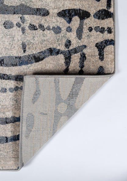 Abstract gray and beige runner rug with navy brushstroke pattern; plush pile, folded corner reveals gray underside.