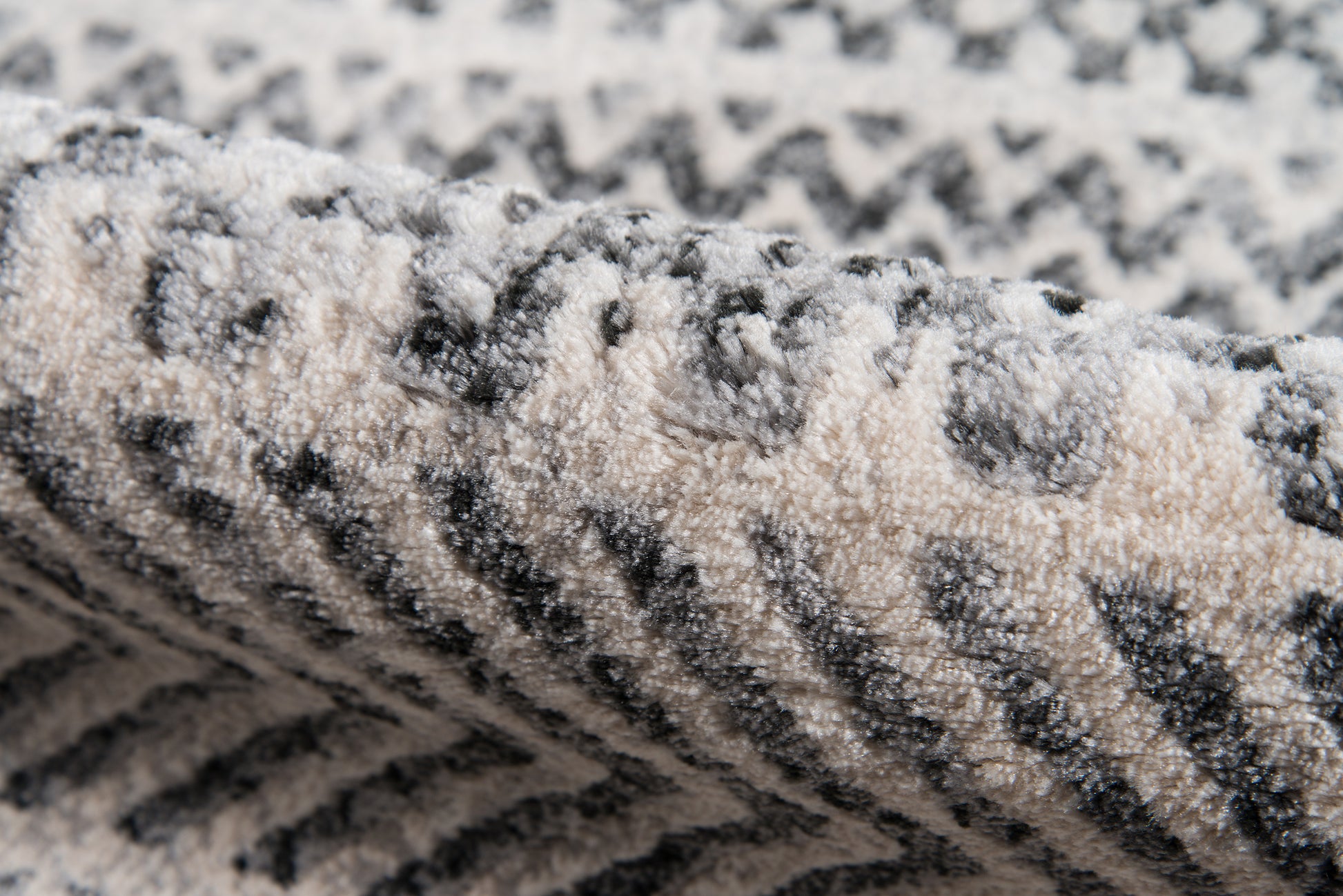 Close-up of a grey & ivory patterned rug with soft, looped pile and chevron zigzags.
