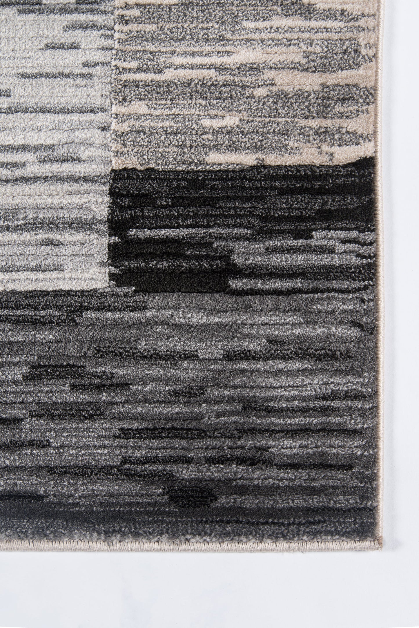 Rectangular grayscale rug with abstract blocky stripes in cream, gray and black; modern textured floor covering.