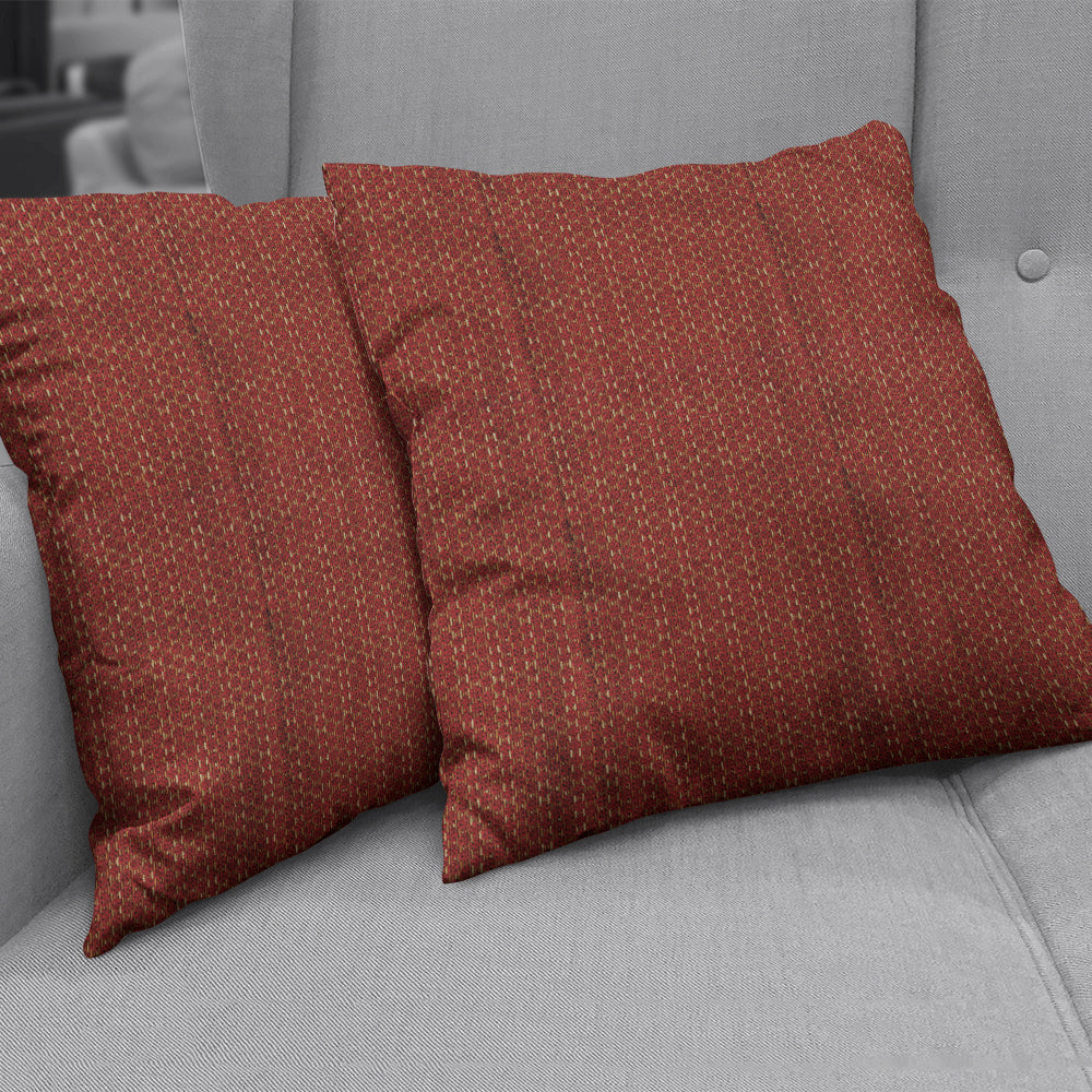 Rust red square throw pillows in a textured woven fabric with a subtle geometric dotted pattern on a light gray sofa.