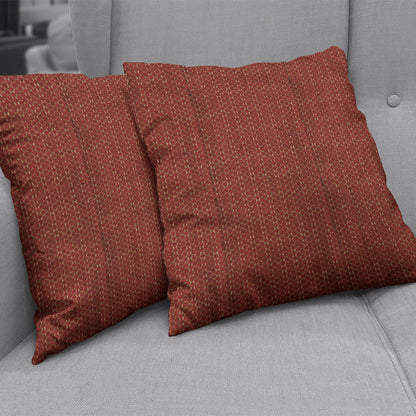 Rust red square throw pillows in a textured woven fabric with a subtle geometric dotted pattern on a light gray sofa.