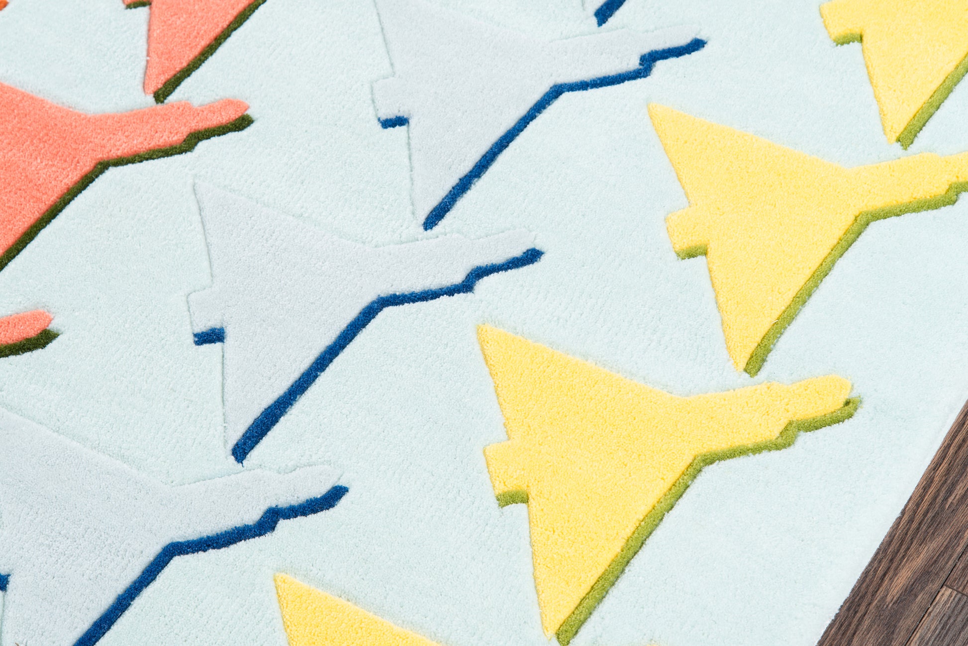 Pastel blue background with repeating yellow bird silhouettes and blue zigzag lines on a rug; playful textile pattern.