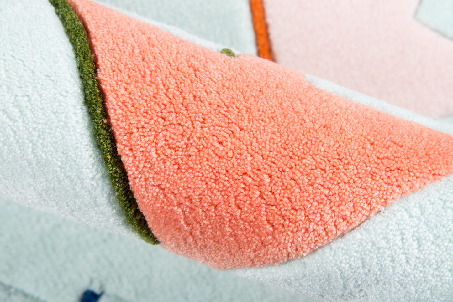 Area rug in peach, pink, mint blue and green accents, folded for display.