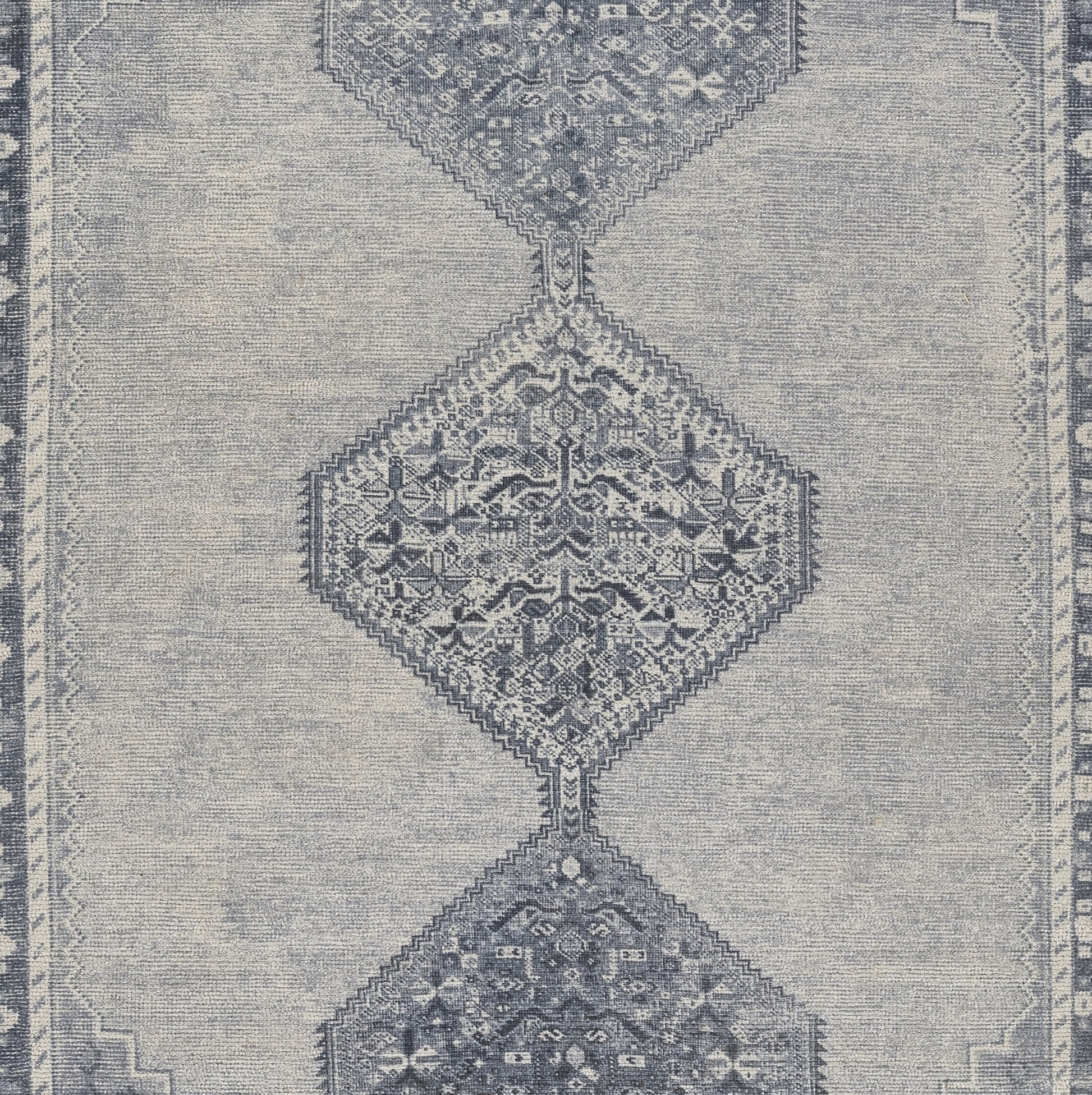 Blue-gray rug with a vertical chain of diamond medallions, intricate floral motifs, distressed texture, and bordered edges.