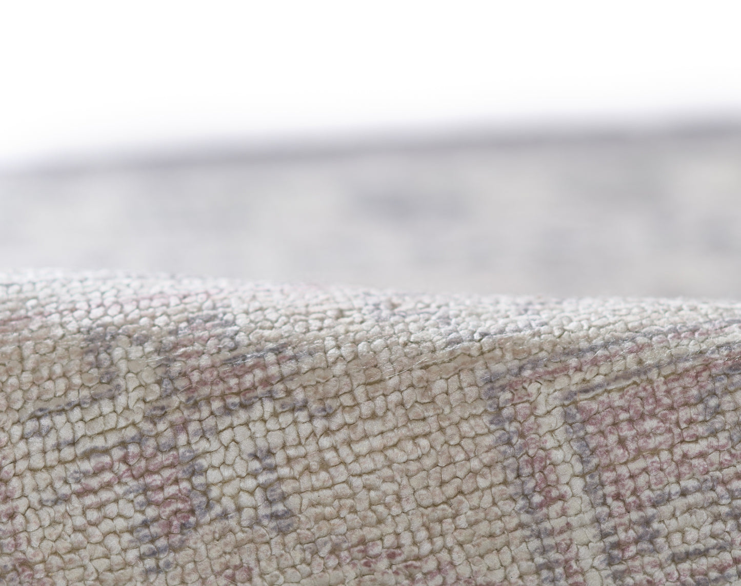 Close-up of textured beige runner rug with tiny loop pile and subtle pink geometric border pattern.