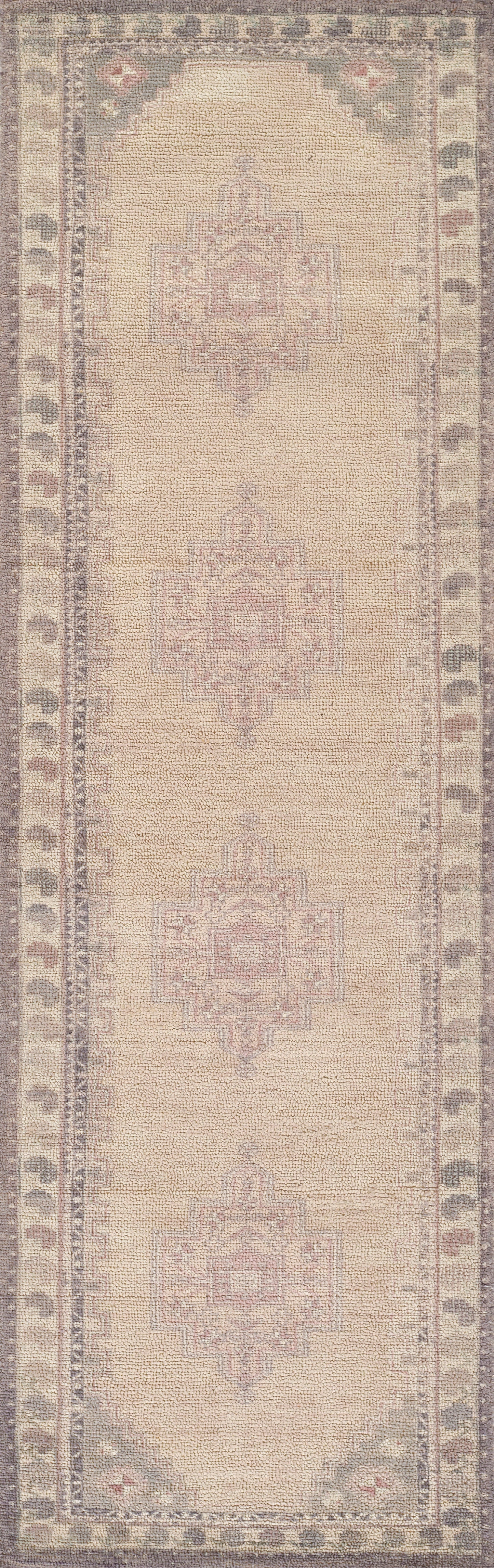Beige Persian-style rug with faded pink-gray geometric medallions and muted taupe border; vintage look, low pile, 5' x 8'.