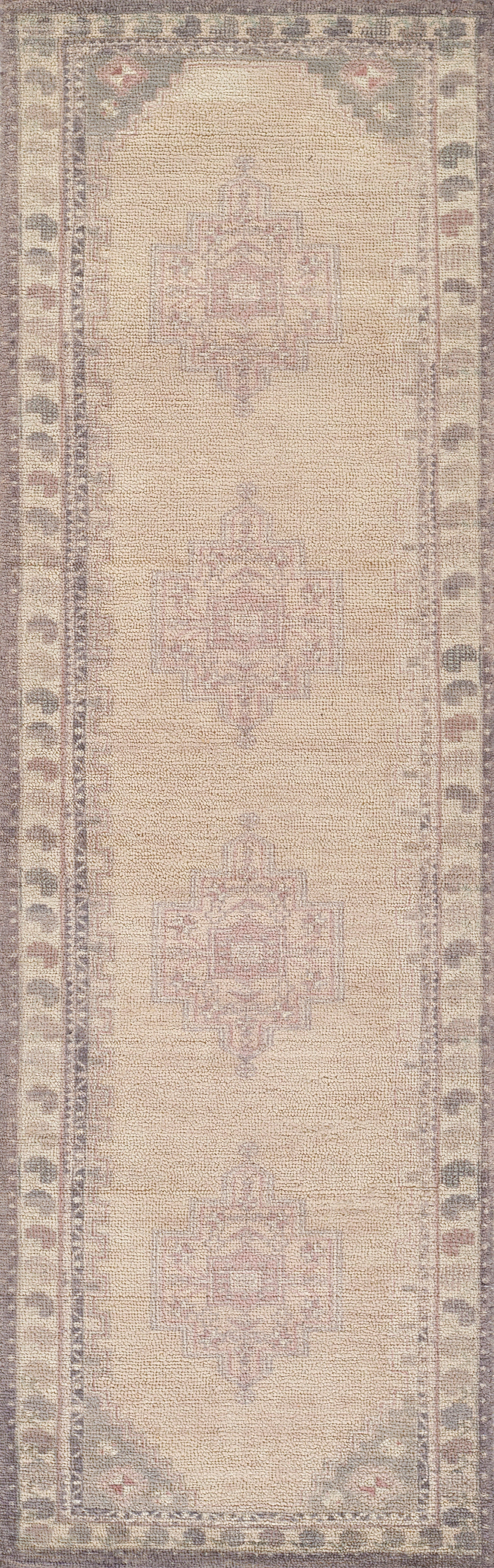Beige oriental rug with soft pink central medallions and muted blue-gray border; woven texture.