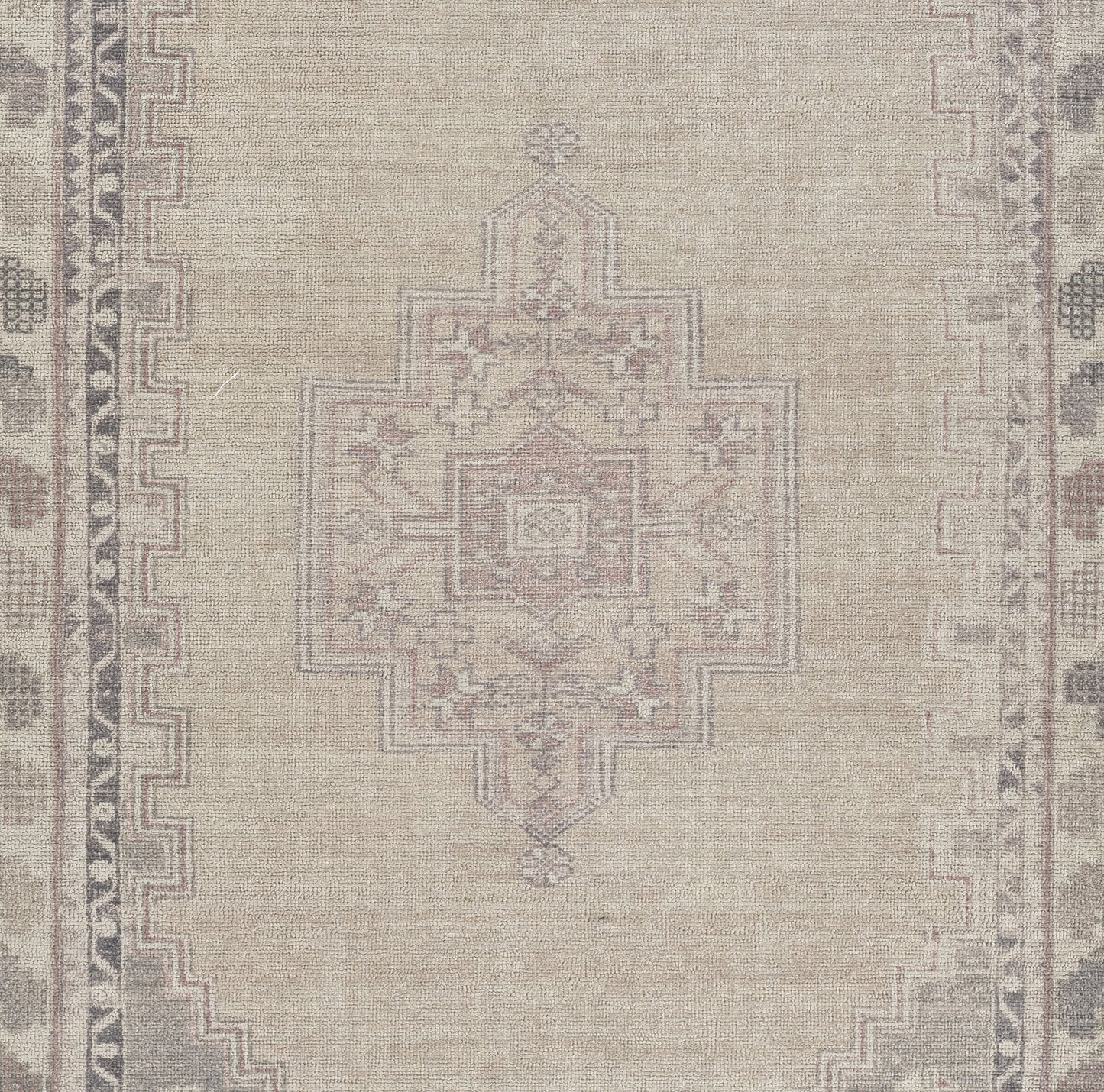 Beige Persian-style area rug featuring a pale pink-gray central geometric medallion and decorative border.