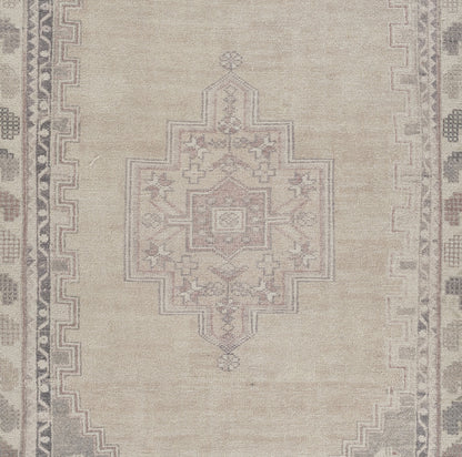 Beige Persian-style area rug featuring a pale pink-gray central geometric medallion and decorative border.