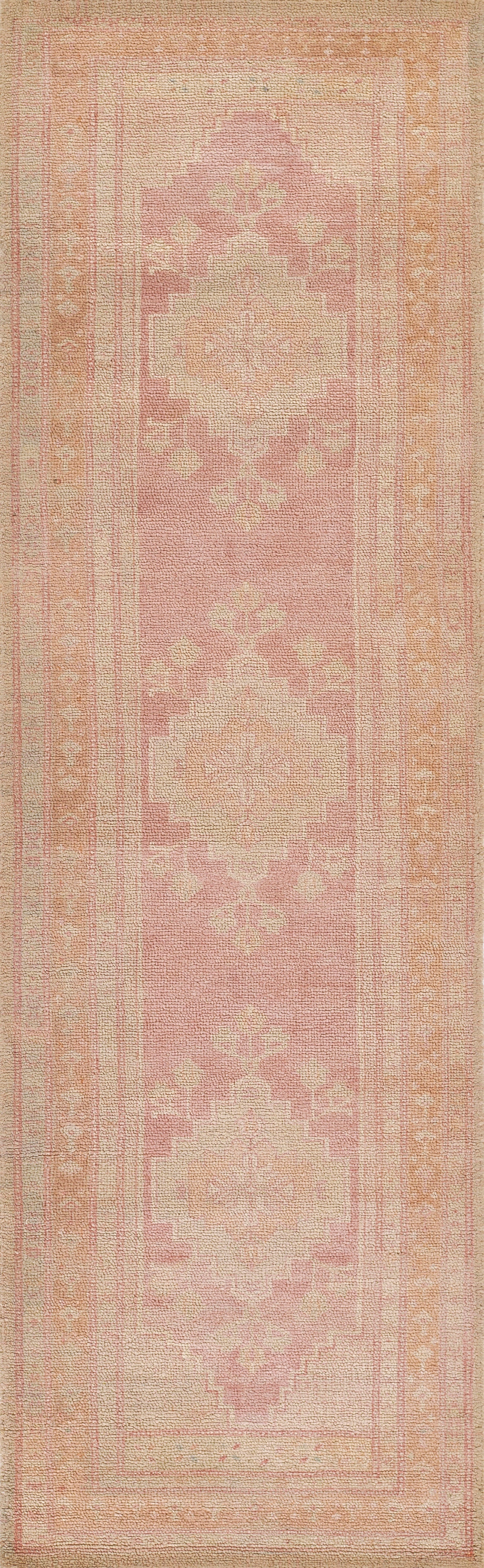 Pink 2' x 4' rug with cream geometric medallions in a vintage oriental pattern and a soft pastel border.