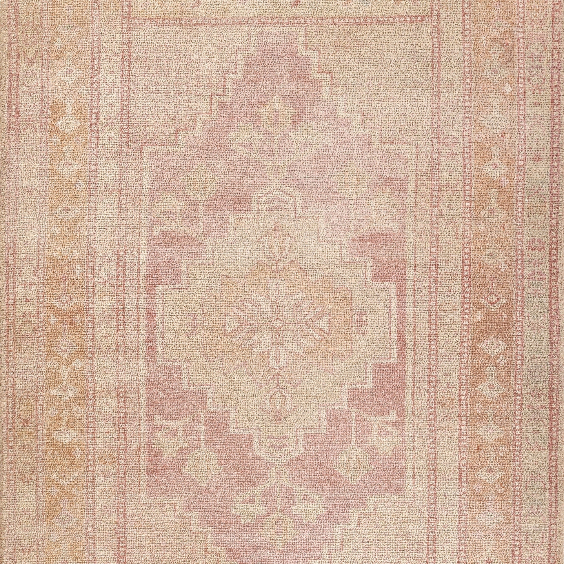 Peach-pink vintage Persian-style woven rug with ivory center medallion, stepped borders and subtle floral patterns