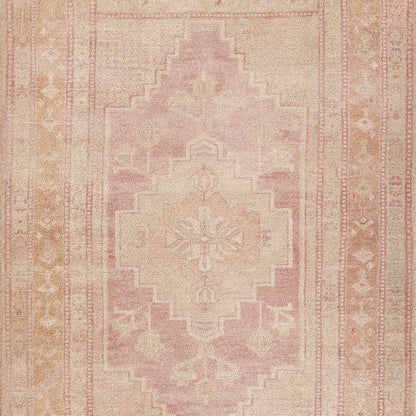 Pastel pink vintage-style area rug with a stepped central medallion, peach and ivory tones, and floral border pattern.