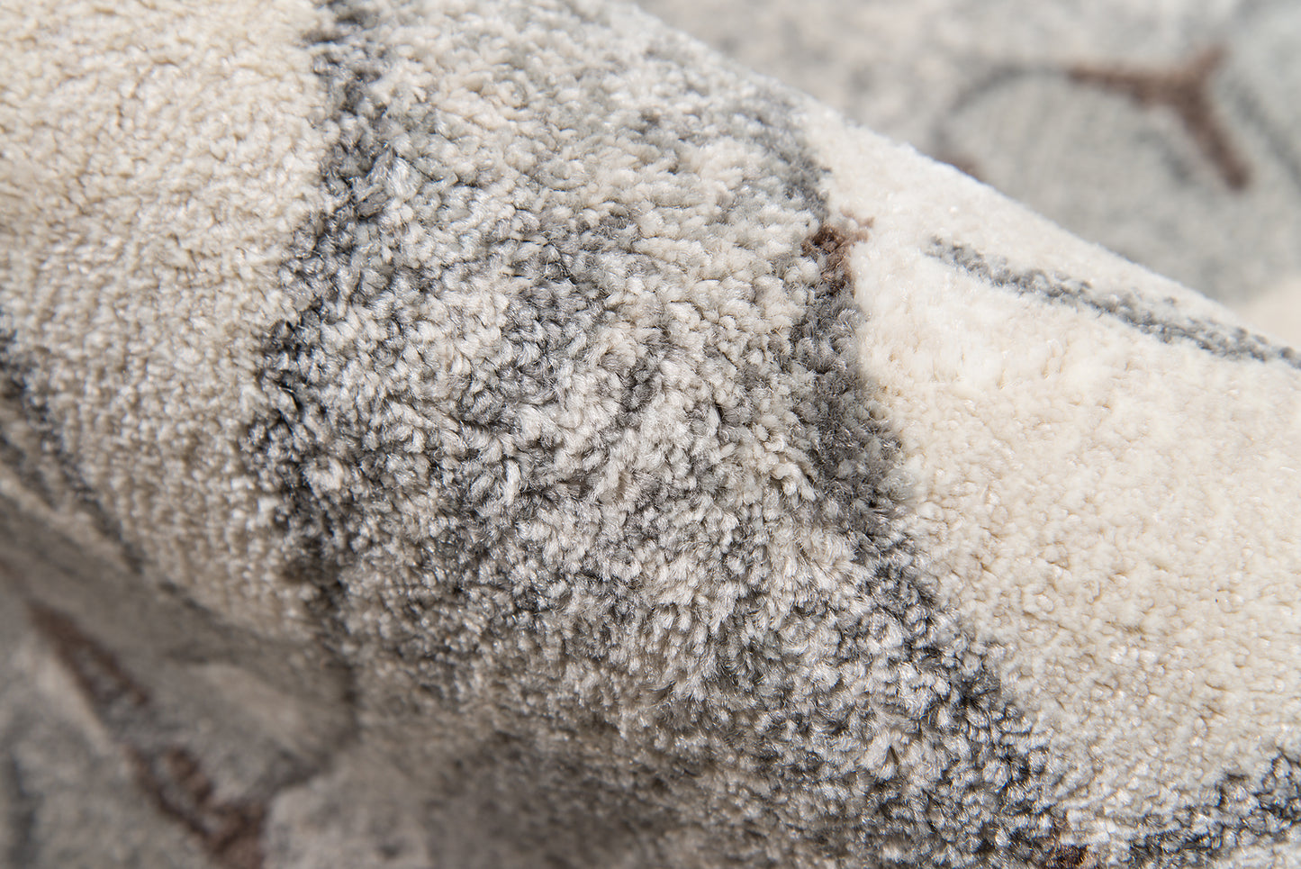 Close-up of a plush beige-gray rug with dense shag pile and subtle geometric lines.