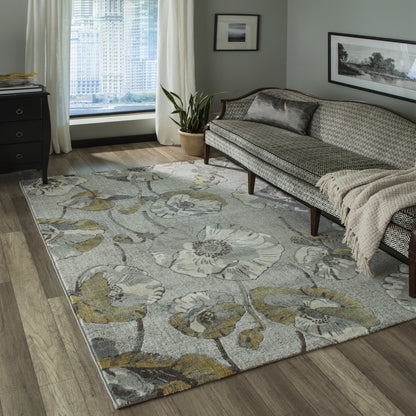 Gray floral area rug with olive and tan accents on wood floors under a patterned sofa in a modern living room.