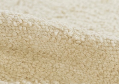 Cream sherpa boucle fabric close-up; soft, chunky texture in beige for cozy clothing or throws.
