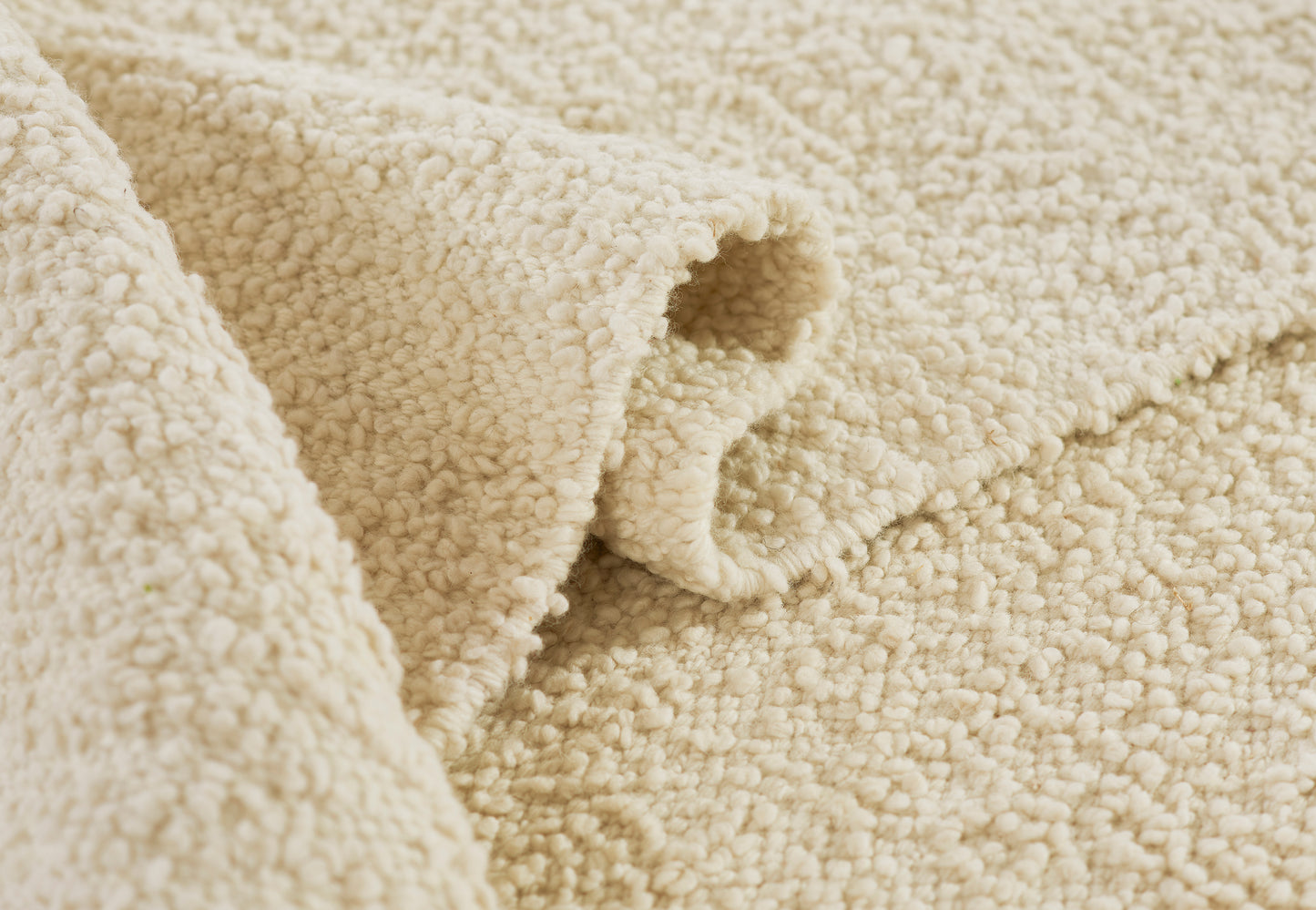 Cream sherpa fleece close-up with plush loop texture, rug material.