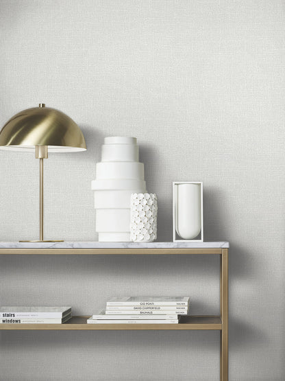 Brass dome lamp on marble shelf with white ceramic vases, smooth and pebbled textures, and a stack of design books.