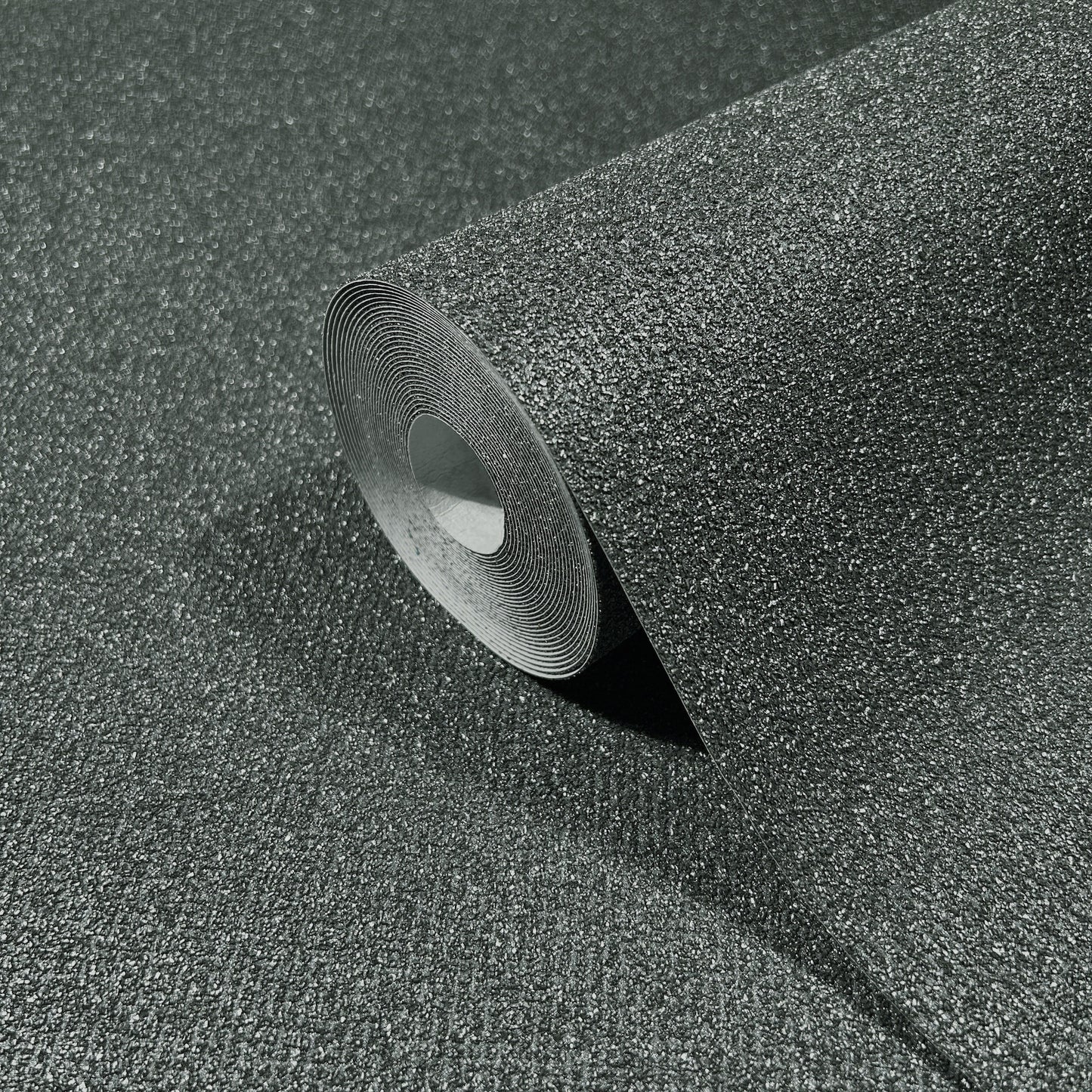 Close-up of dark gray granulated asphalt roofing membrane roll, peeled edge exposing white core.