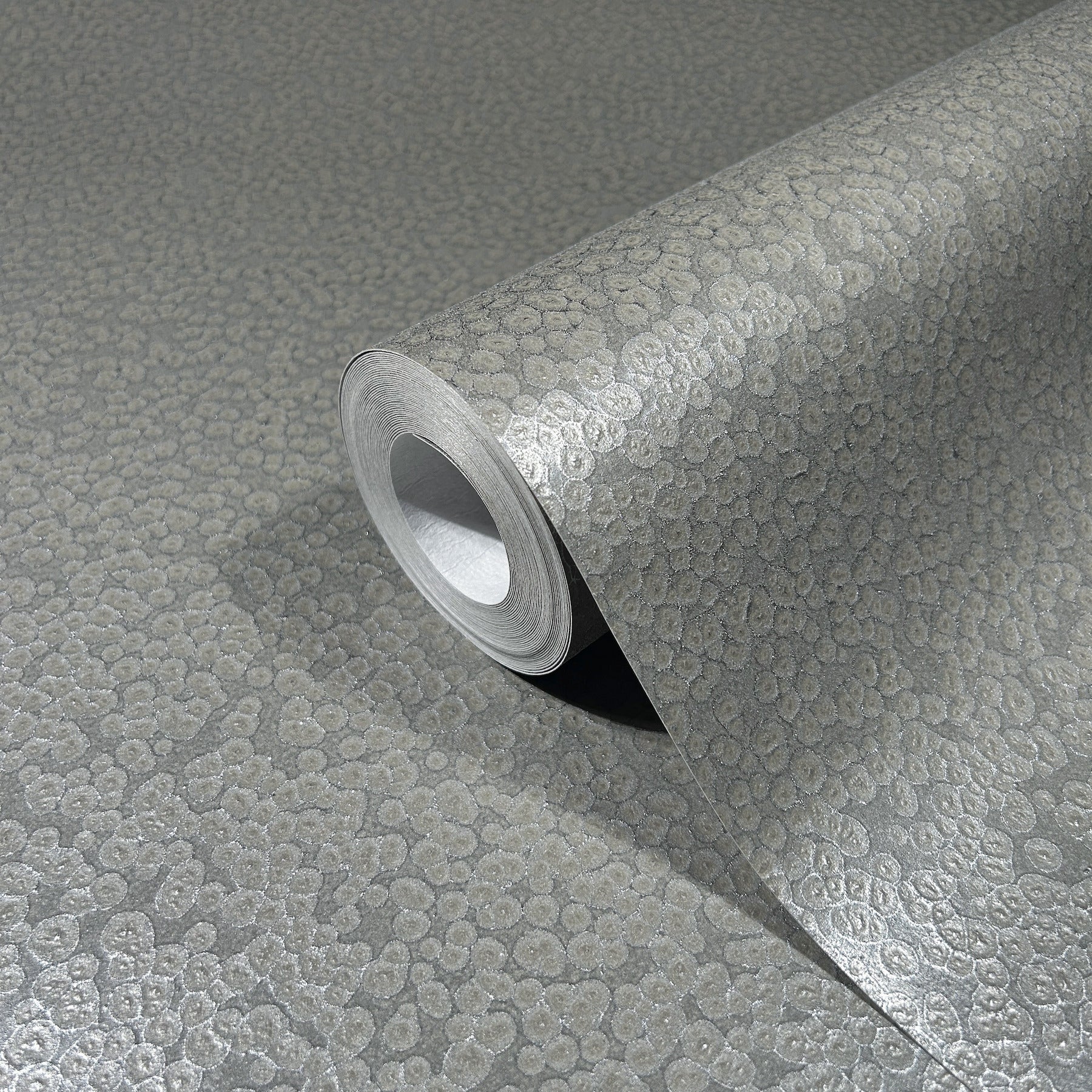 Silver metallic wallpaper roll with pebble-textured embossed surface for accent walls.