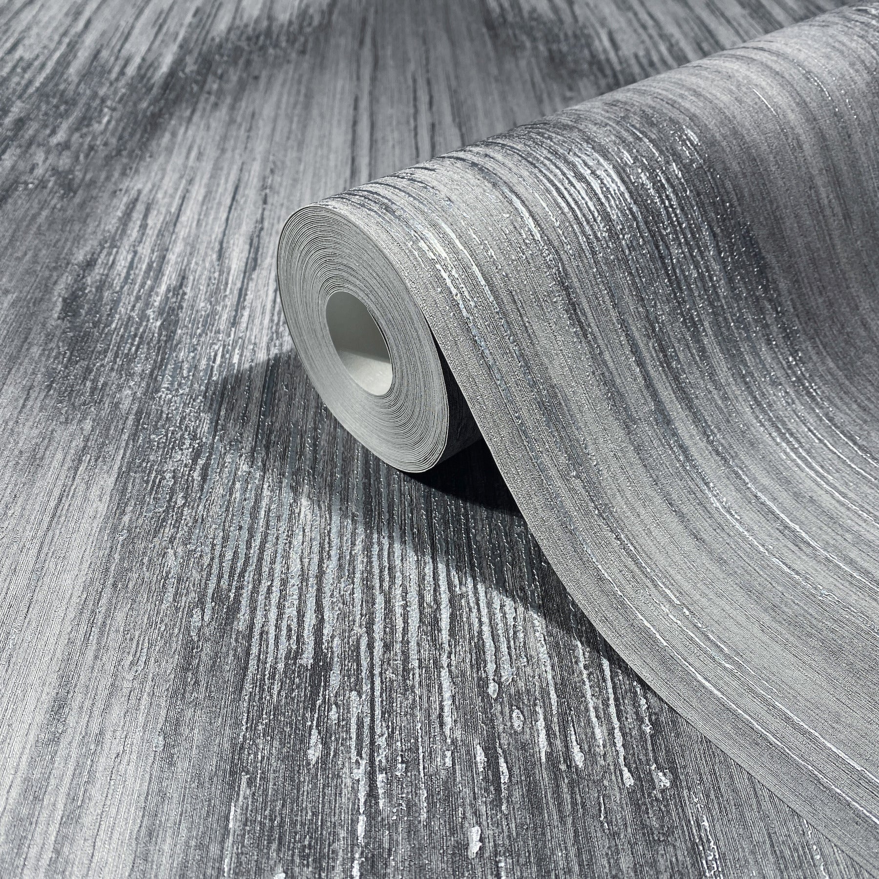 Rolled grey textured flooring sample with silver-white linear streaks, partially unrolled to reveal brushed surface.