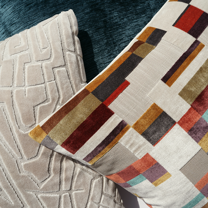 Beige textured pillow with geometric embroidery on teal surface.