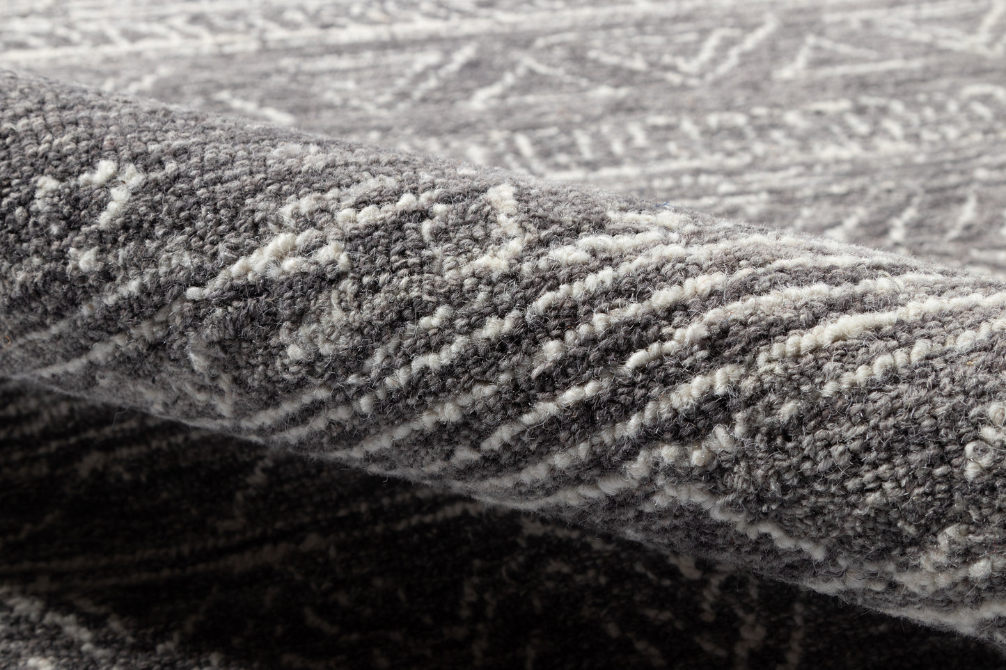 Close-up of a gray patterned rug with soft plush pile and woven geometric design.