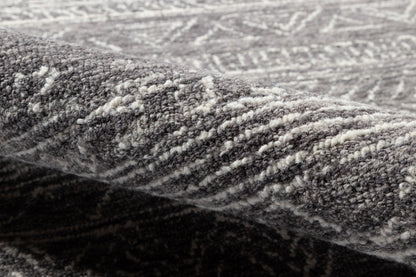 Grey patterned rug close-up with textured pile and folded edge; modern home decor.