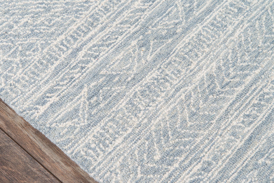 Blue and white flatwoven rug with a diagonal geometric pattern on a wooden floor.