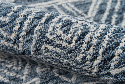 Close-up of a blue and cream geometric rug with a diamond motif and soft woven pile.