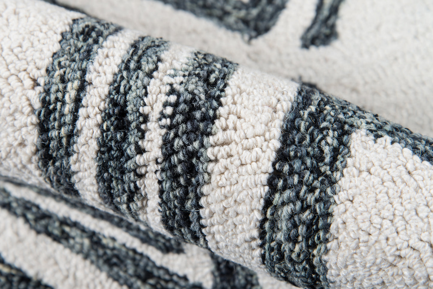 Close-up of a textured looped-pile rug in cream and charcoal gray stripes.
