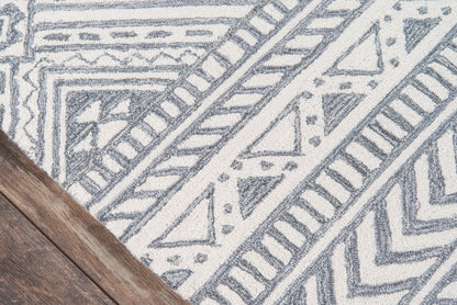 Gray and white geometric tribal-pattern rug with angular motifs; wooden floor corner visible.