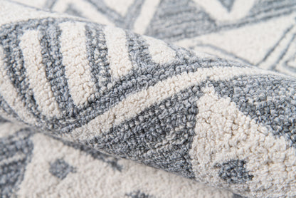 Close-up of a blue-gray and ivory geometric woven rug with striped and triangular patterns; soft textured fabric.