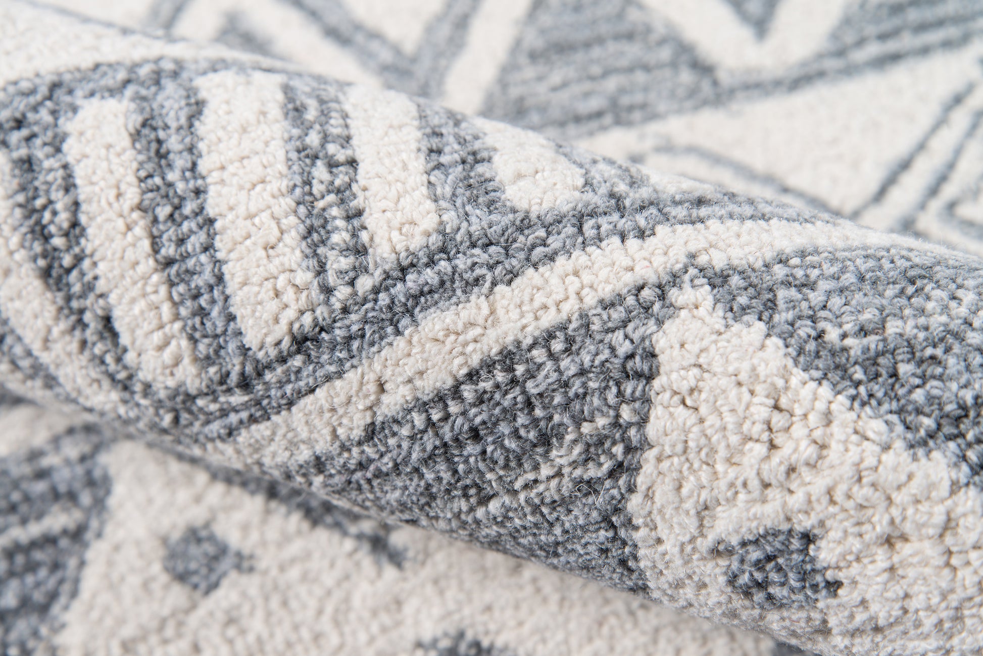 Close-up of a gray and cream textured woven rug with geometric chevron pattern and plush pile.