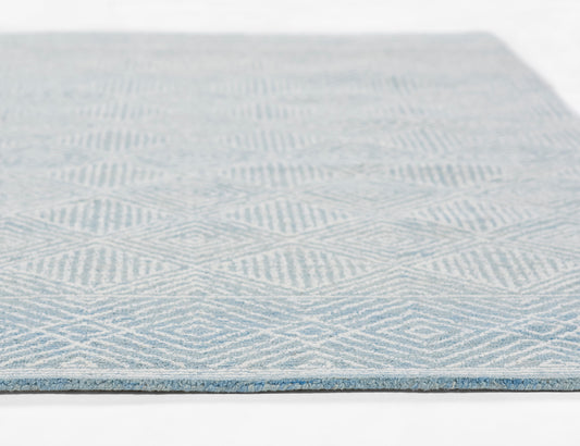 Light blue flat-weave rug with a subtle diamond geometric pattern and darker blue border.