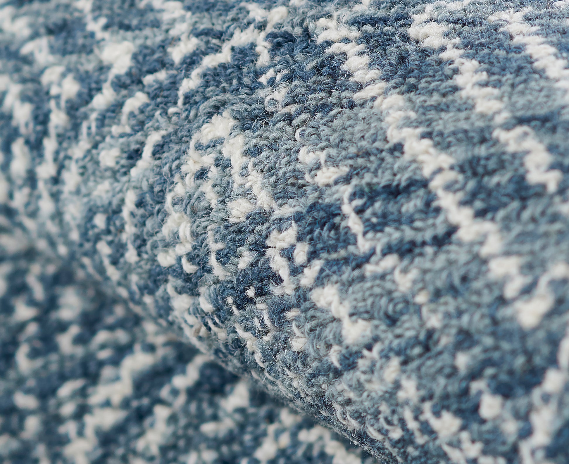Close-up of a blue and white woven rug with a textured loop pile and abstract geometric pattern.
