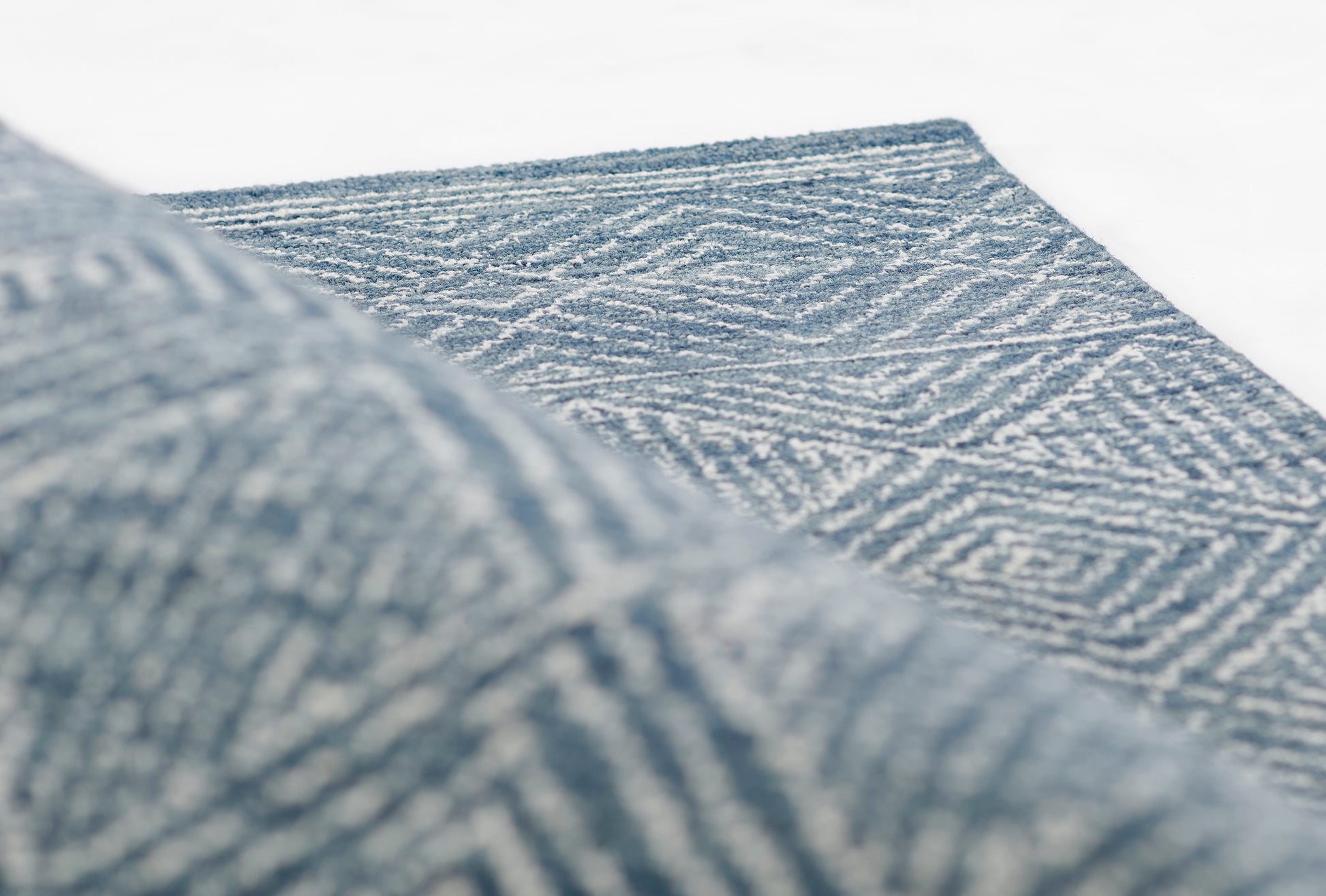 Blue-grey woven rug with chevron-like geometric pattern and textured pile.