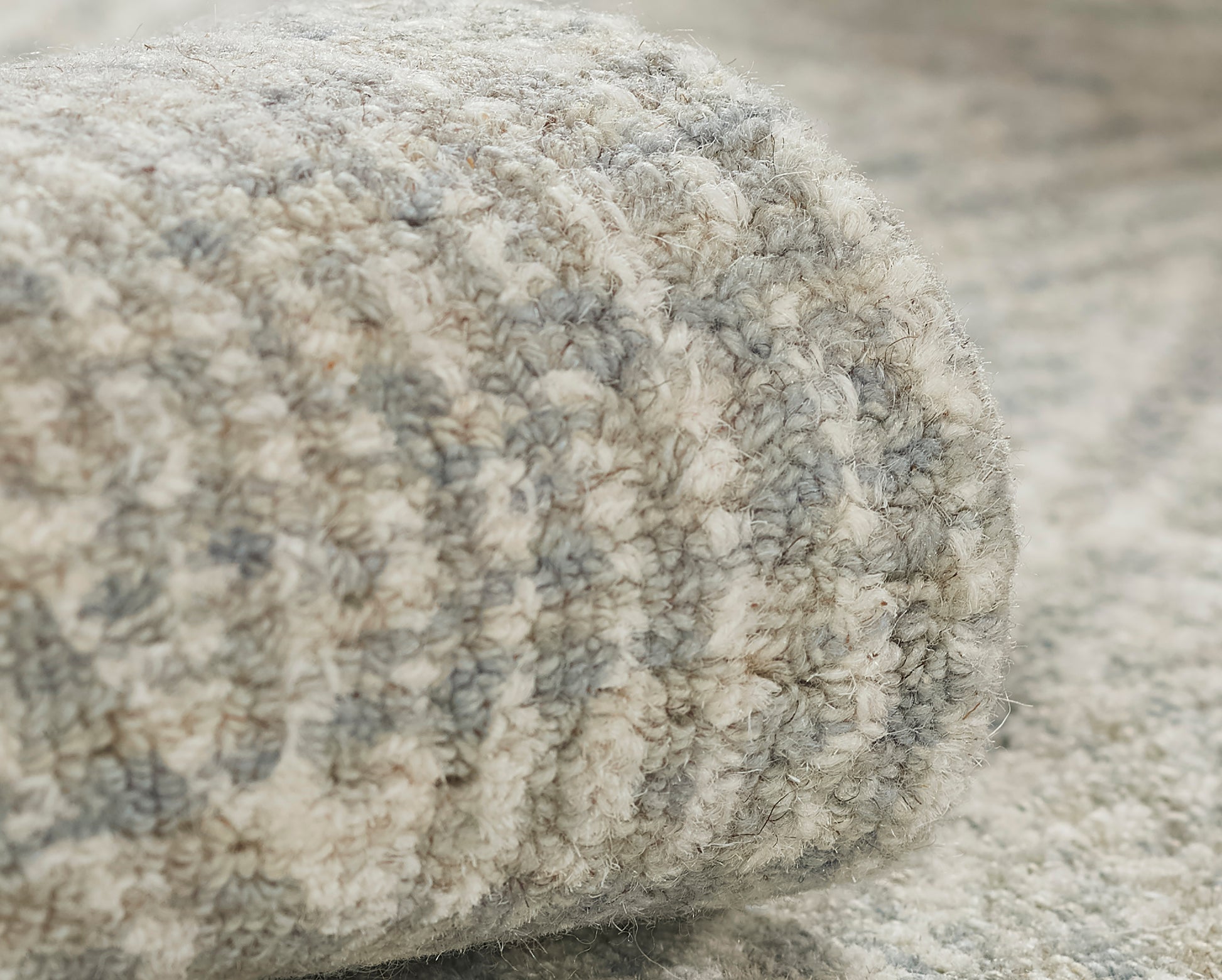 Close-up of a soft gray and cream boucle rug with thick textured pile.