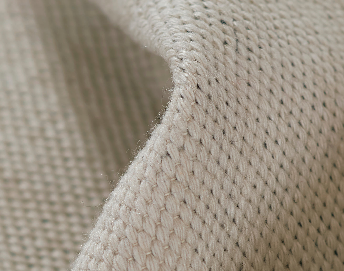Ivory knitted textile close-up with chunky weave; soft cozy fabric suitable for throws or blankets.