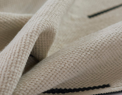 Ivory knitted rug with chunky texture and a dark navy stripe.