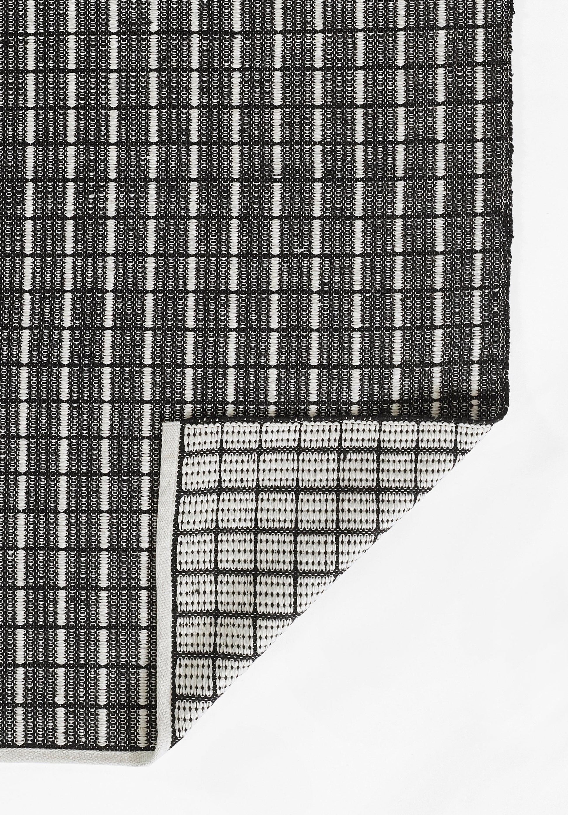 Gray gradient rug with a black-and-white woven strip at the bottom left and a white triangular corner.