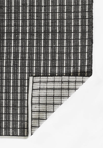 Gray gradient rug with a black-and-white woven strip at the bottom left and a white triangular corner.