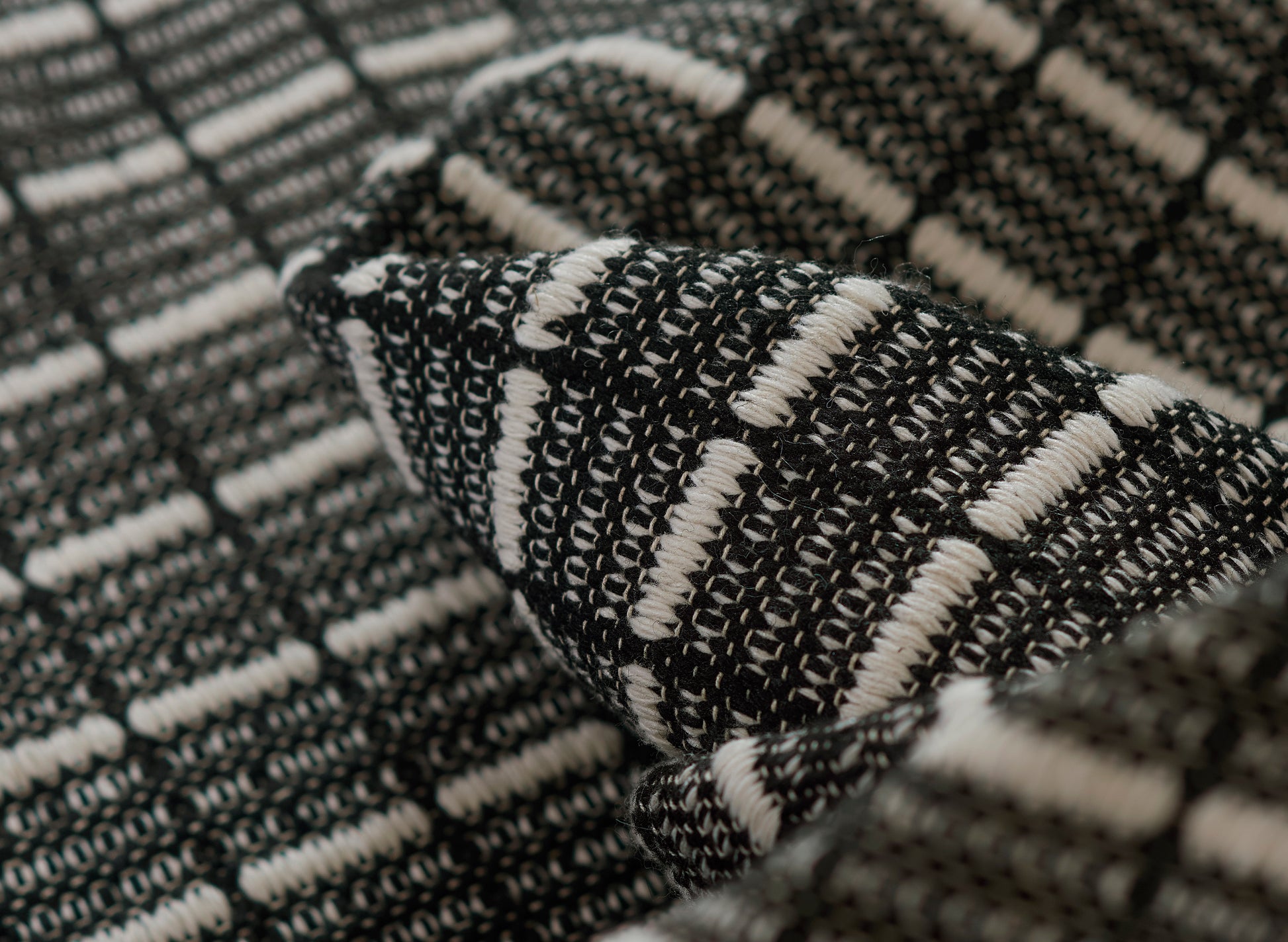 Close-up of black and white woven fabric with chunky striped plaid texture.