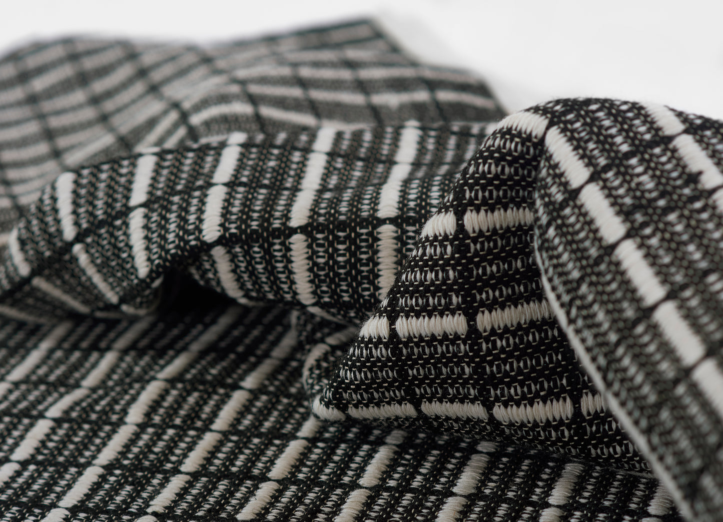 Black-and-white woven fabric with a grid pattern; soft scarf or throw textile.