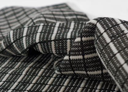 Close-up of black and white woven rug with geometric striped pattern, folded to show texture.