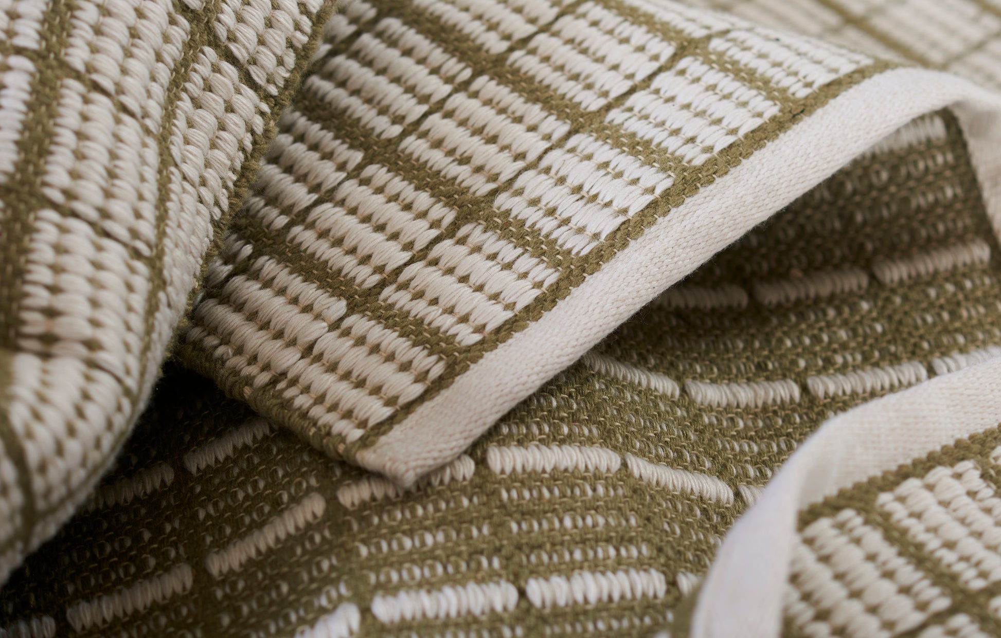 Olive and cream checkered woven throw blanket, soft textured fabric, folded for display.